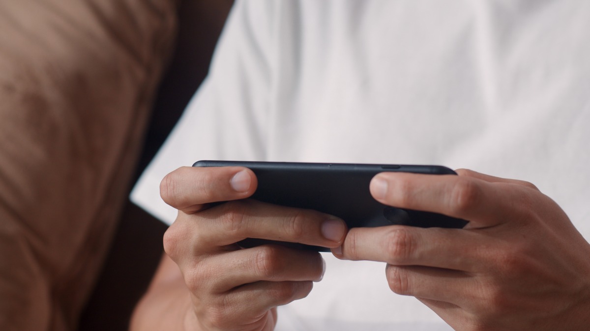 遊戲玩家多日未上線 隊友跨國報警卻傳噩耗 young asian man using mobile phone playing video games television living room male feeling happy using relax time lying sofa home men play games relax home