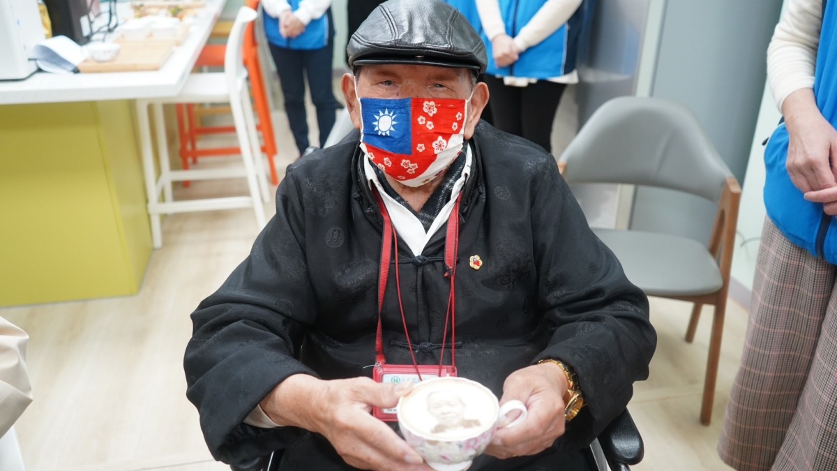 輔導會吳志揚八德榮家拜年 關懷長輩提前賀元宵 八德榮家104歲彭爺爺看著印有自己人像的奶泡咖啡開心不已