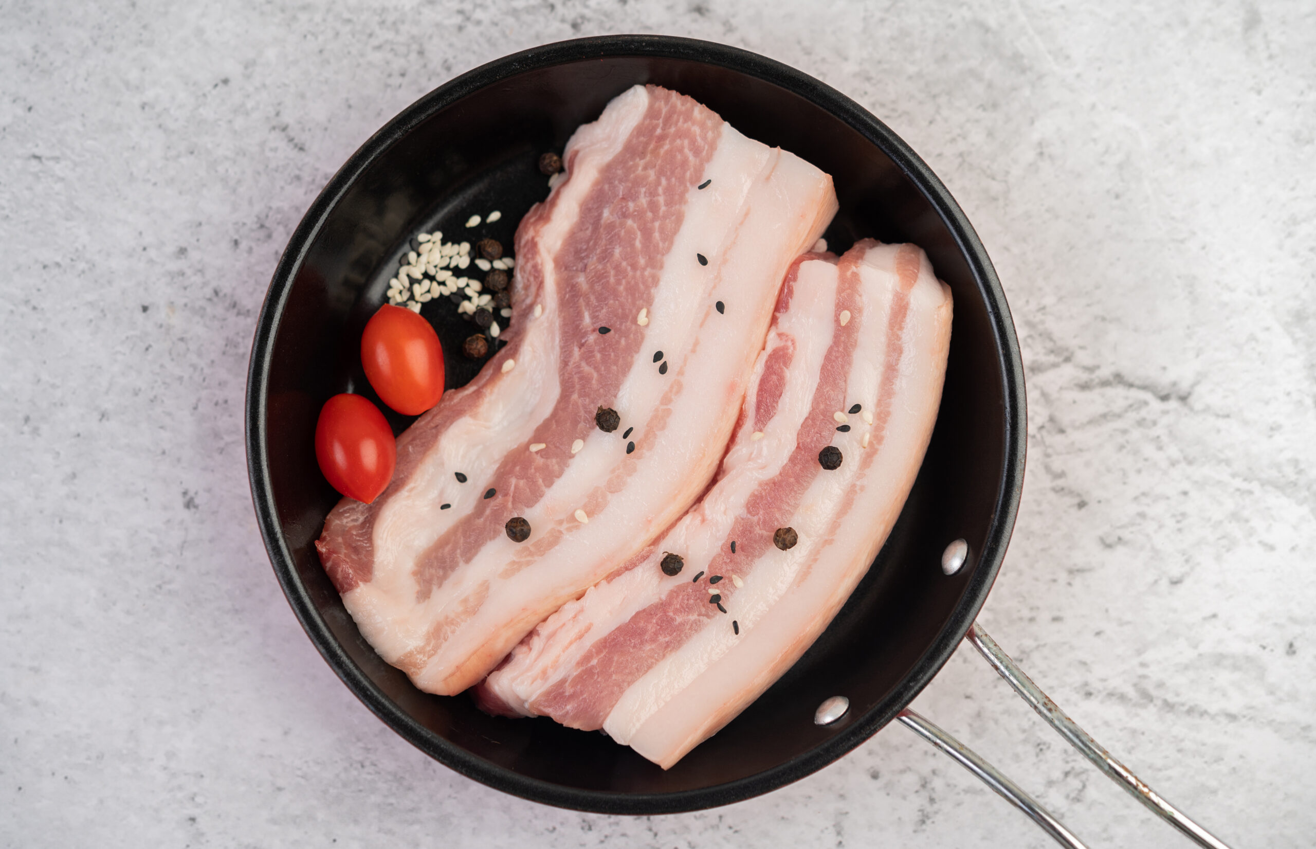pork belly pan with pepper seeds tomatoes spices scaled