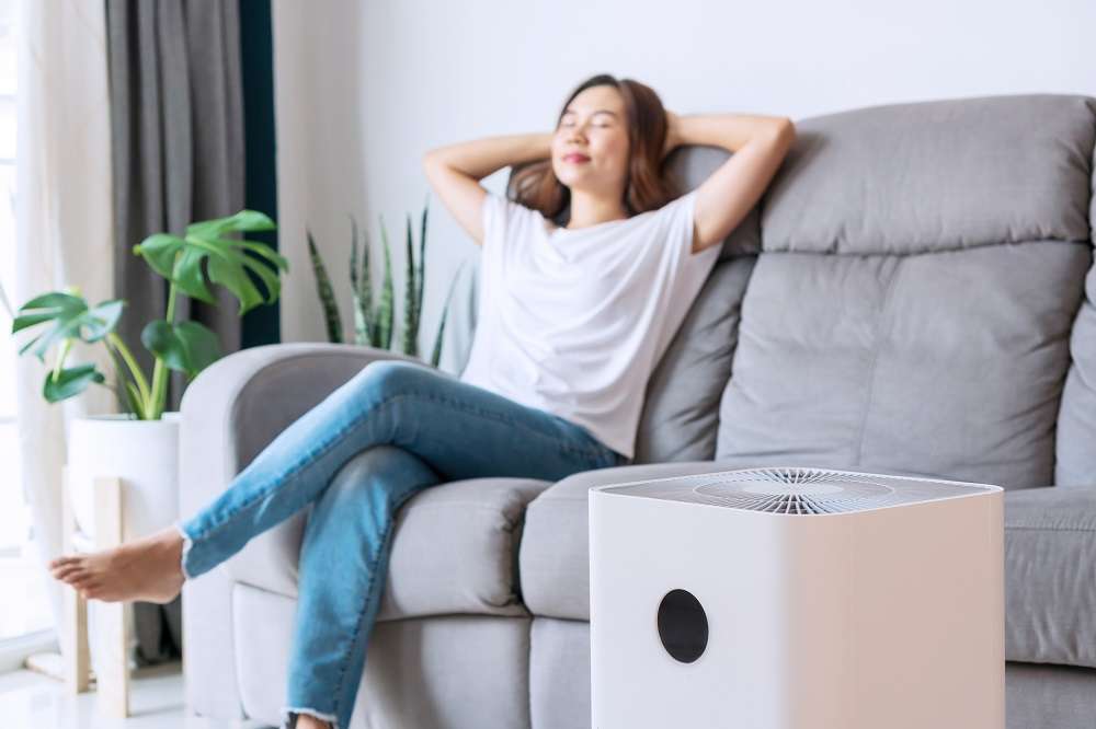 能坐就不站?研究指每日久坐9小時 死亡風險增22% asian woman relaxing comfortable sofa home with purifier beside