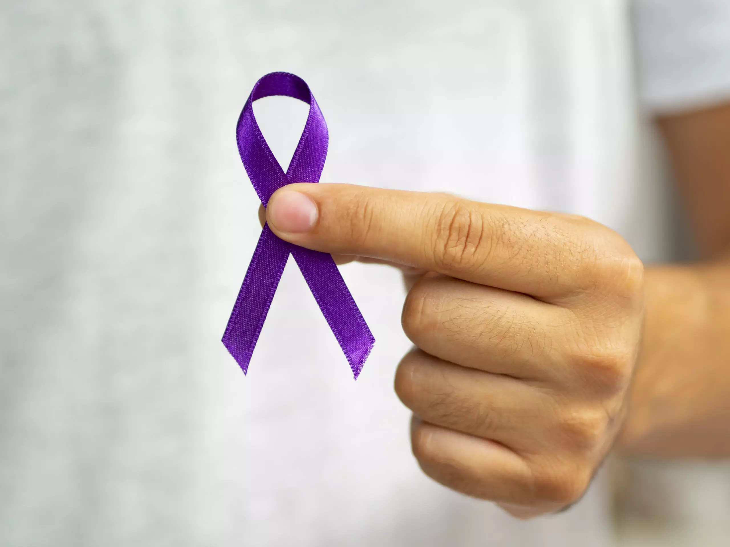 close up person holding up purple ribbon scaled