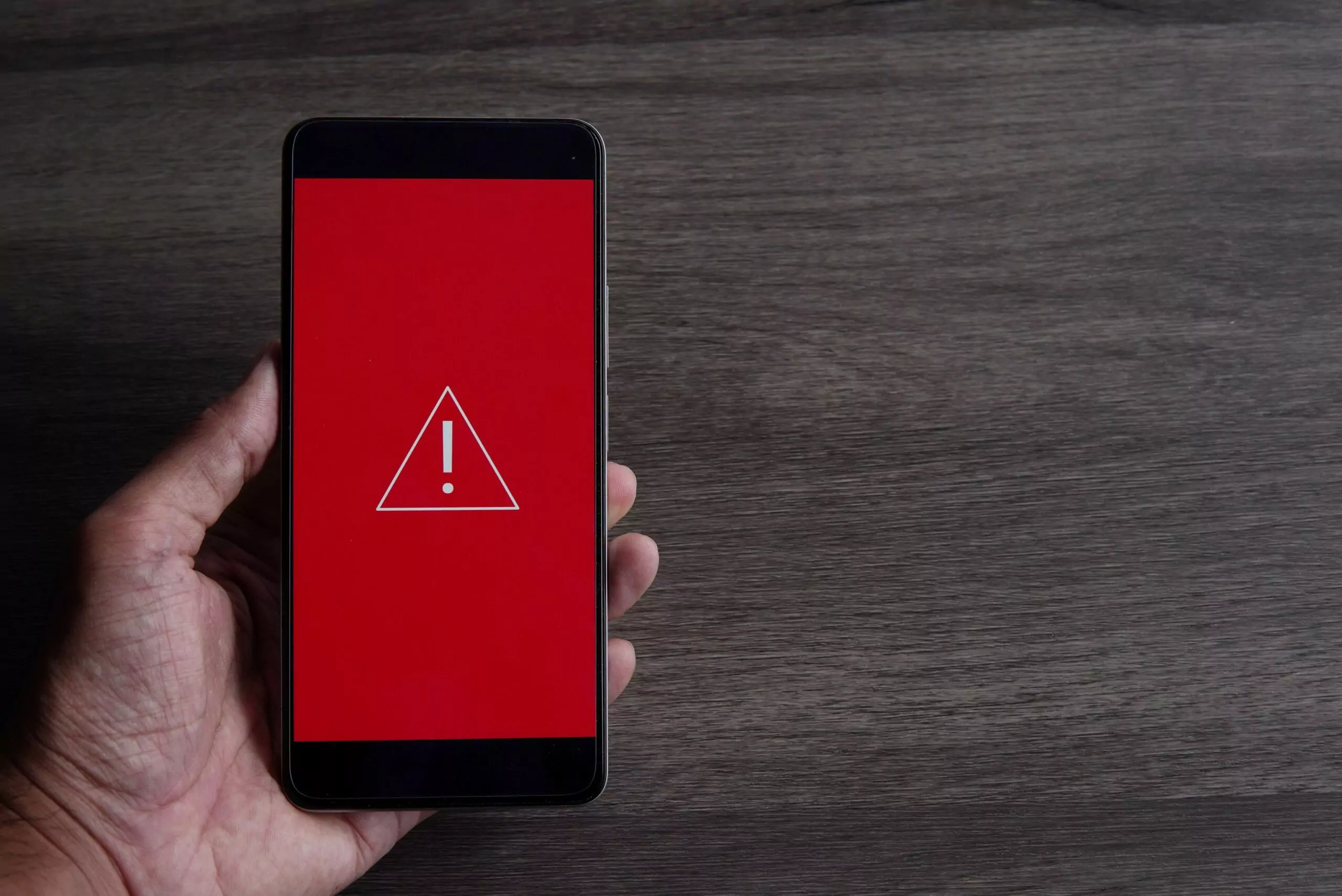 smartphone with triangle caution warning icon copy space text system error malware cyber crime scaled