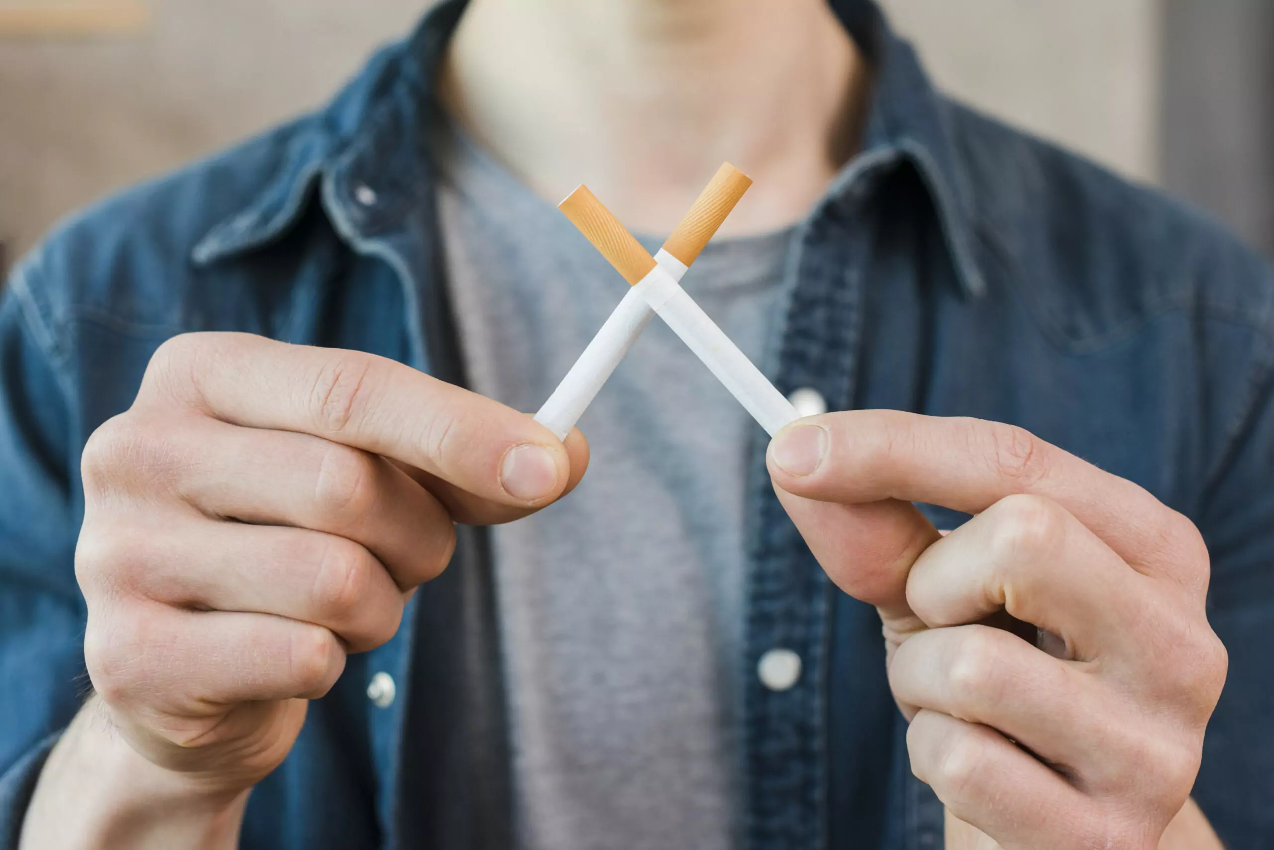 man s hand holding crossed cigarettes scaled