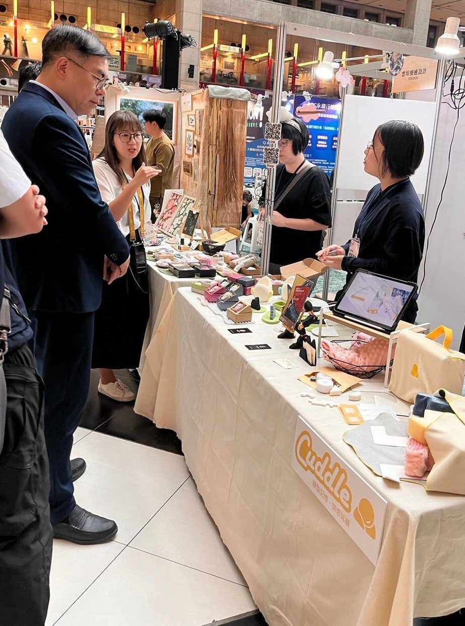 中原大學商設系參加循環經濟新創展 廢棄制服變身午睡枕材料包 02 環境部部長彭啓明左1至中原商設系攤位給予支持。 0