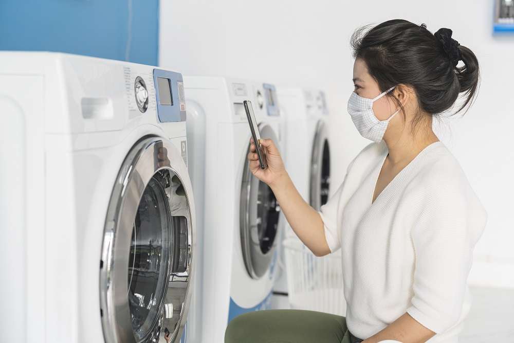 桃園制定自助洗衣店安全管理自治條例 避免發生重大公共意外 portrait female wear virus protecting mask spread covid19 washing blue color interior laundry shop condoiminuim city new normal lifestyle