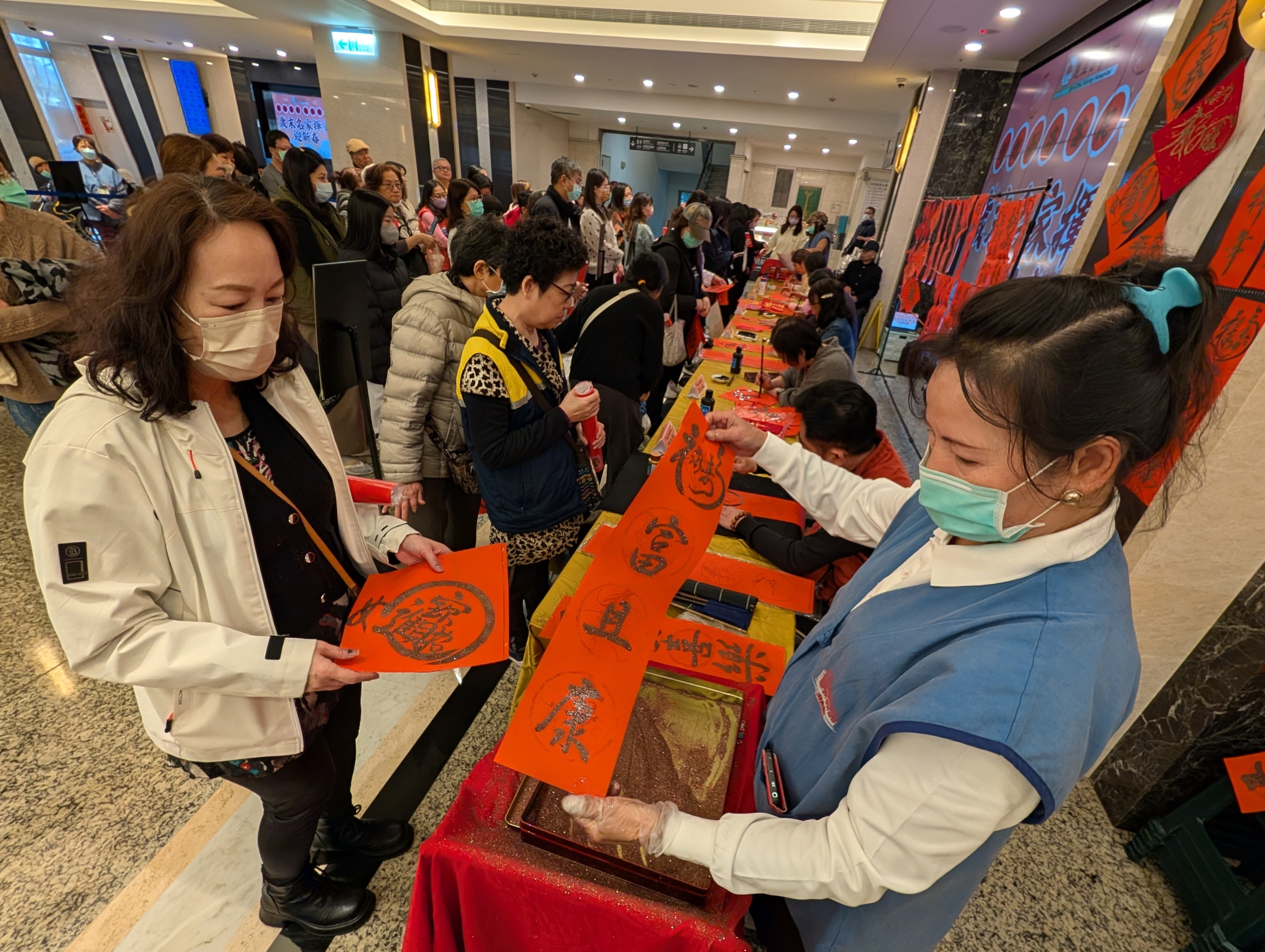 恩主公醫邀書法名家現場揮毫 贈春聯傳遞新年福氣 醫院志工幫民眾春聯撒上金粉添喜氣 2