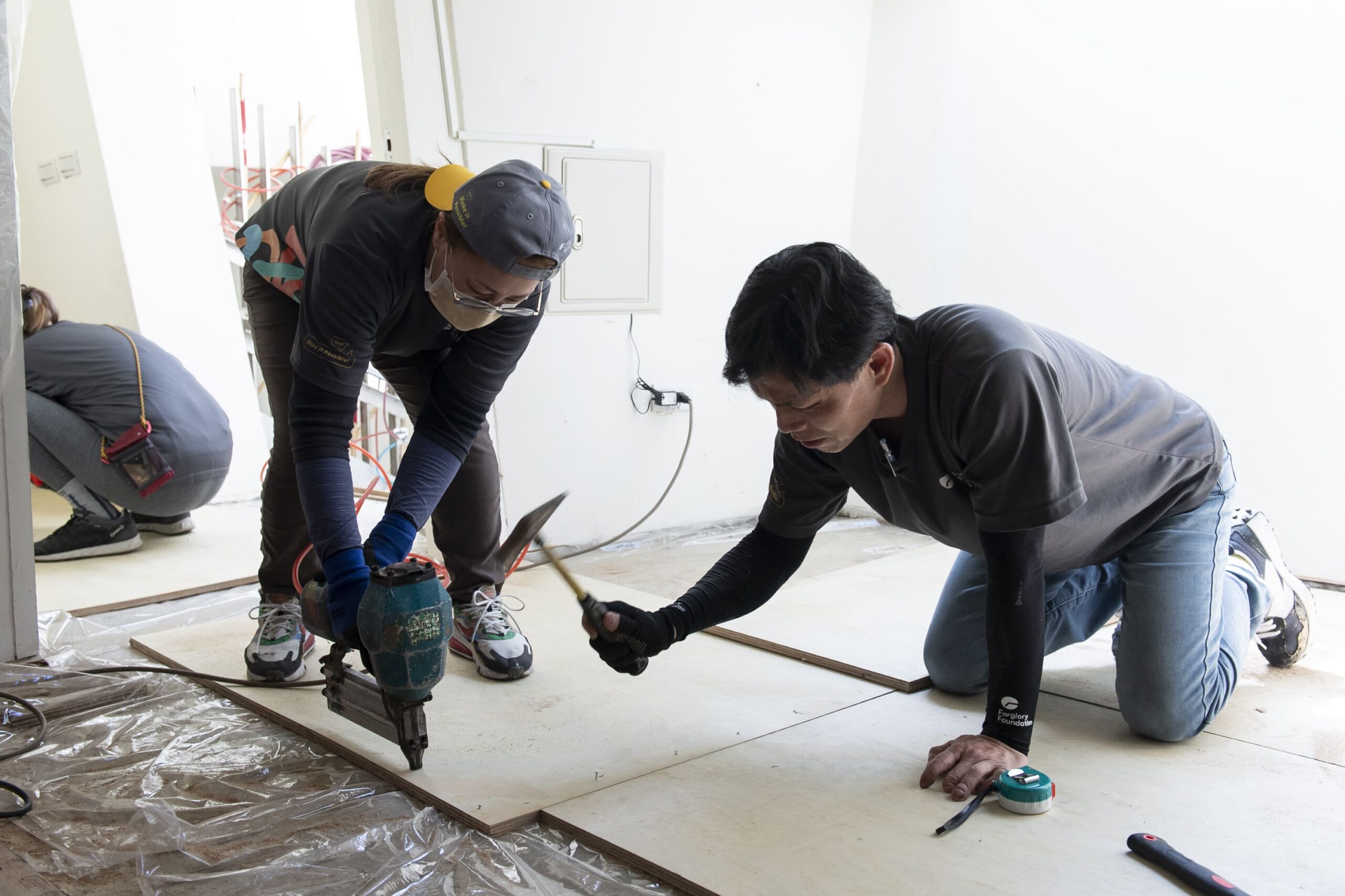 志工們在地面鋪上防潮布後，再固定夾板，以便後續工項施作 scaled